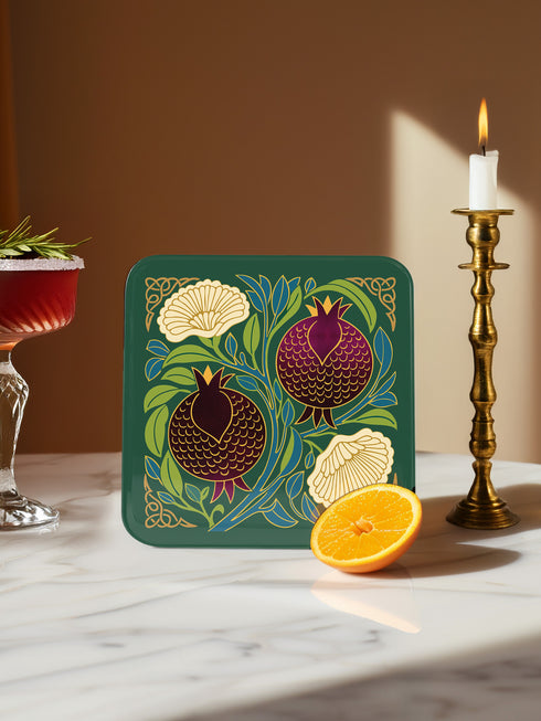 Set of four square drinking coasters featuring rich, dark green botanical illustration with highly detailed Pomegranate fruits and sliced cross-sections. The ornate pattern utilizes deep crimson, opulent gold, and ivory tones, strongly reflecting the stylized Art Nouveau period aesthetic and William Morris textile designs. Crafted from durable, resilient masonite hardboard, this luxury item features a protective high-gloss finish and a non-slip cork base.